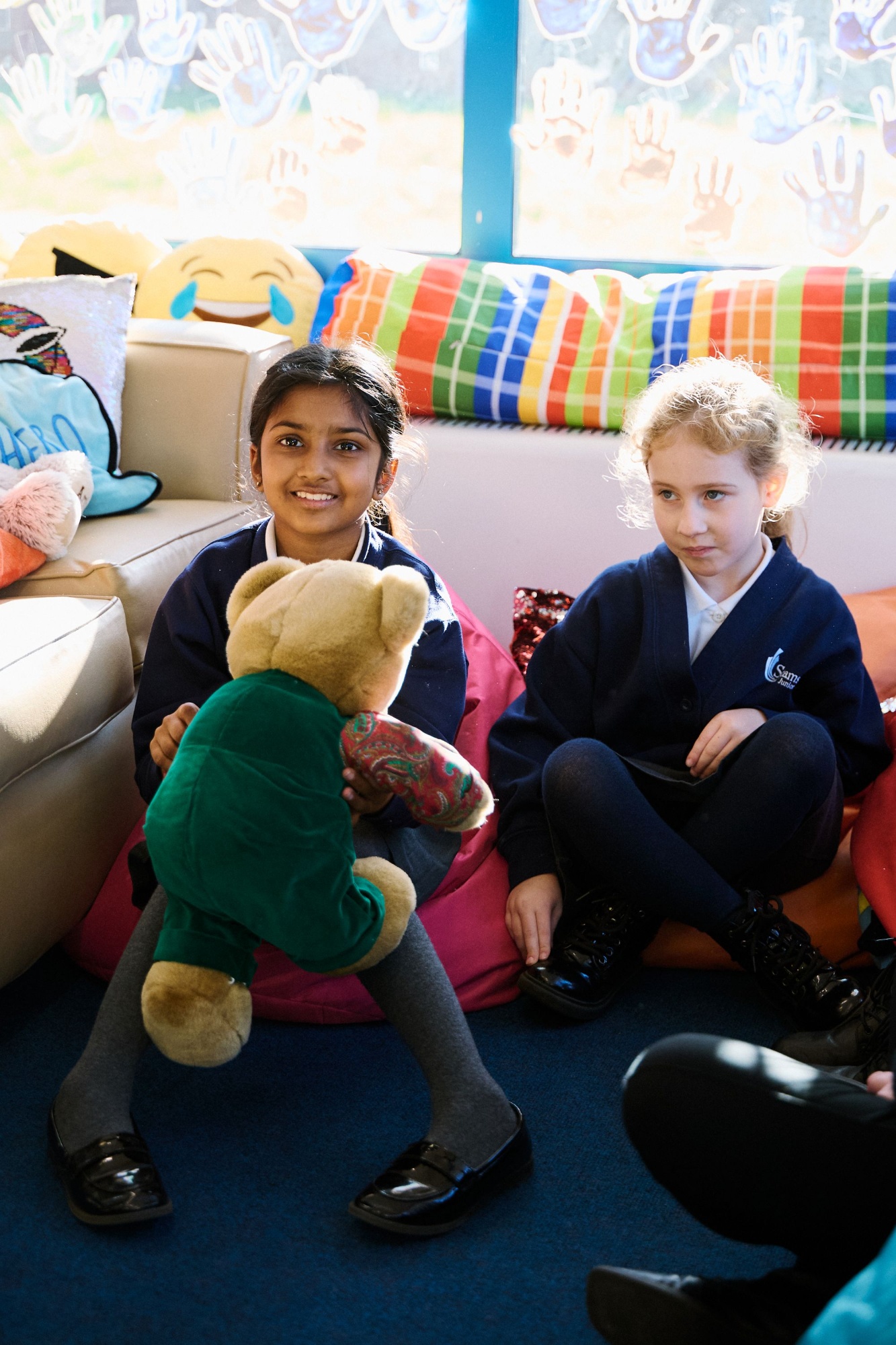 Children sitting on beanbags with a teddy bear