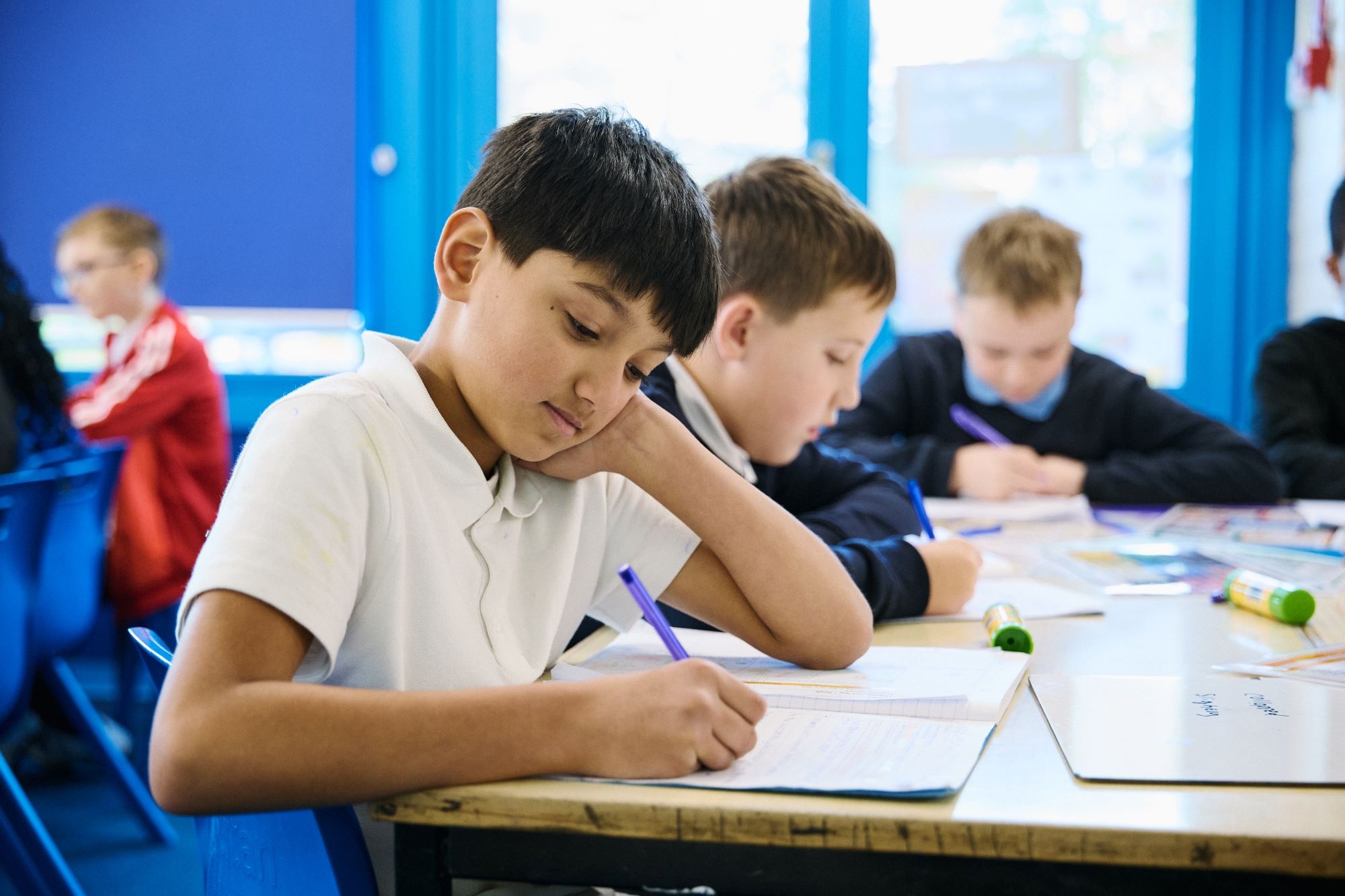 Child writing at a desk in a classroom